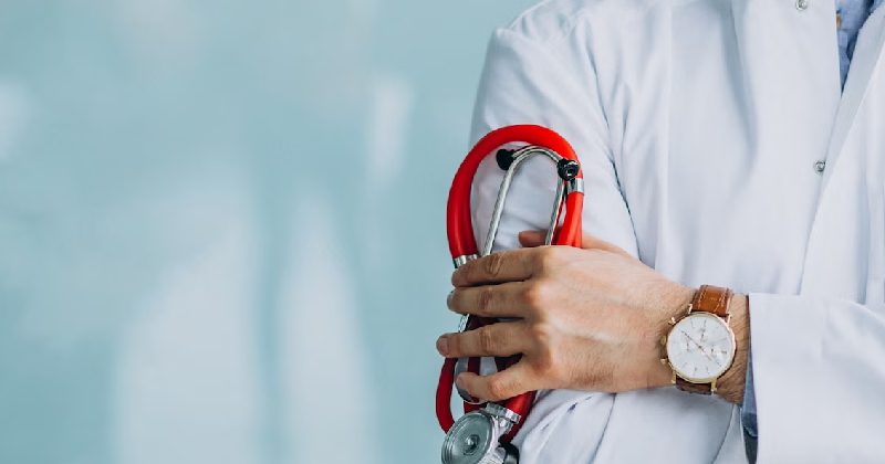 Young handsome physician in a medical robe with stethoscope